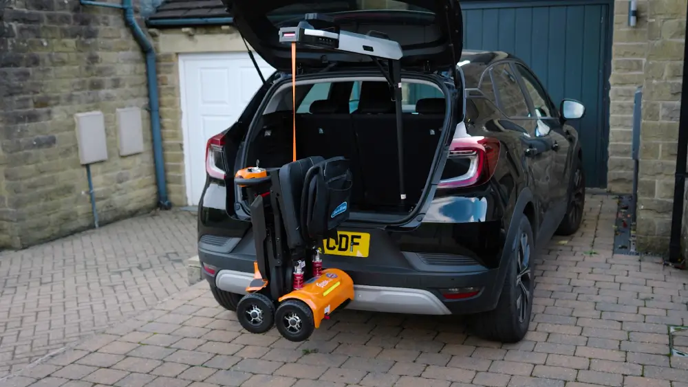 Portable car lift raising a folded orange mobility scooter into an SUV trunk