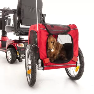 small dog inside a red canvas trailer attached to the back of a mobility scooter
