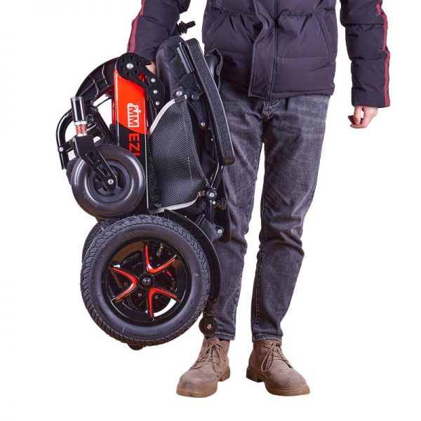 A man holding a folded up Ezifold powerchair