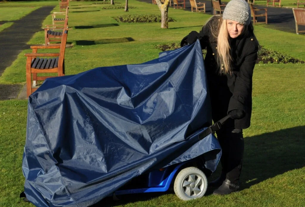 lady putting a cover over a mobility scooter