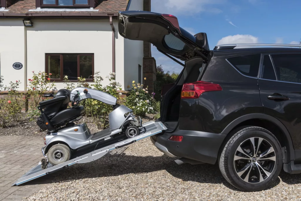 a mobility scooter on a ramp which is resting on a car boot