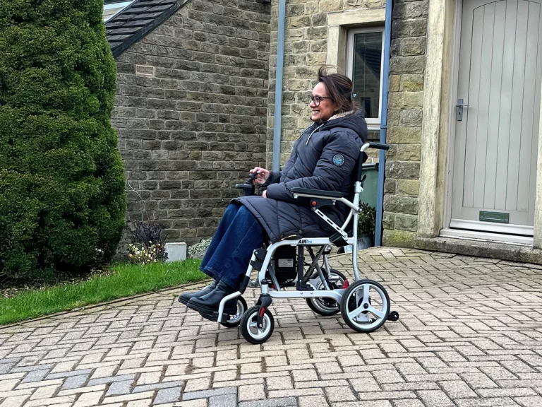 A lady sitting in a powerchair in the driveway of her house