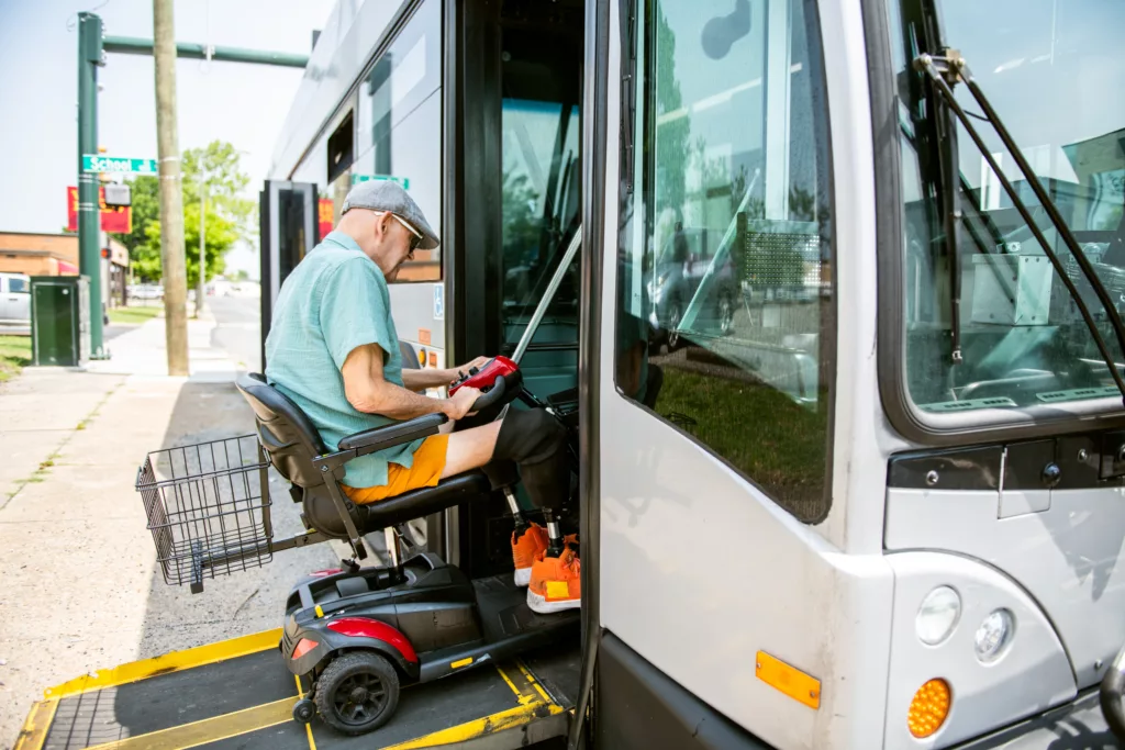 Older man taking a mobility scooter onto a bus