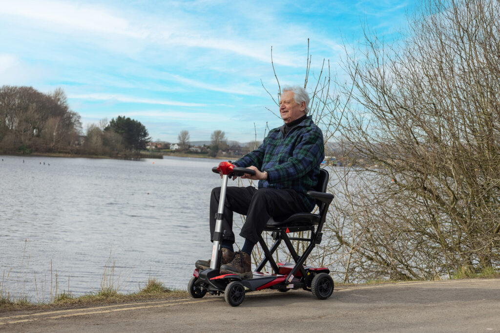 a man riding a Smarti mobility scooter alongside a lake