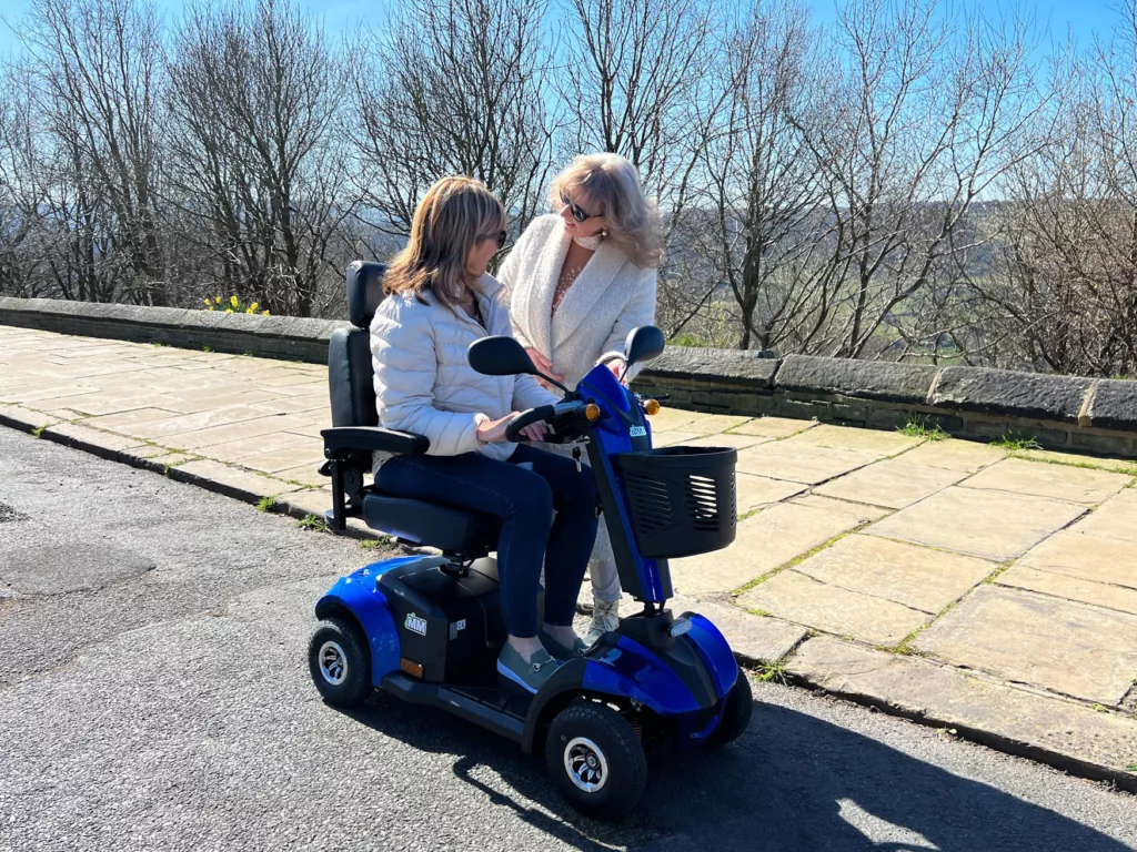 Lady on a mobility scooter chatting to a friend on the pavement