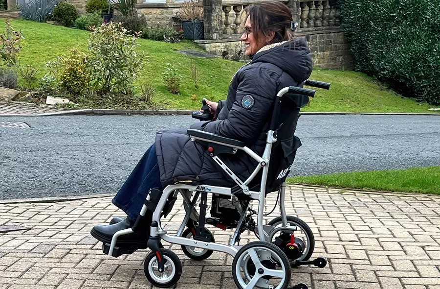Lady driving a powered wheelchair on a paving area