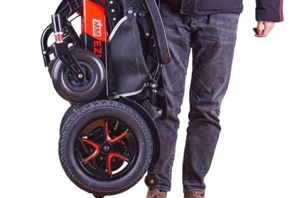 Bottom half of a man showing him carrying a folded up mobility scooter