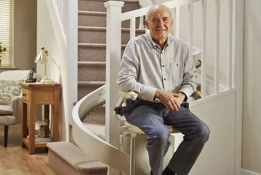 Older gentleman on a stairlift at the bottom of a set of stairs