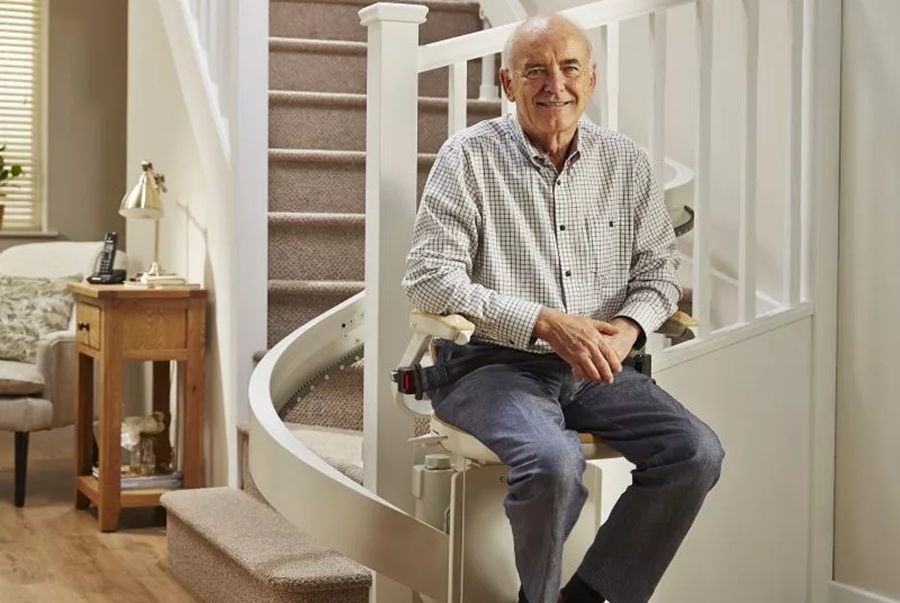 Older gentleman on a stairlift at the bottom of a set of stairs