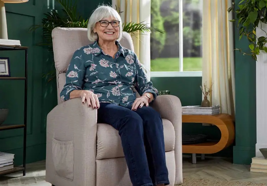 Elderly lady sitting in a cream recliner chair in her sitting room