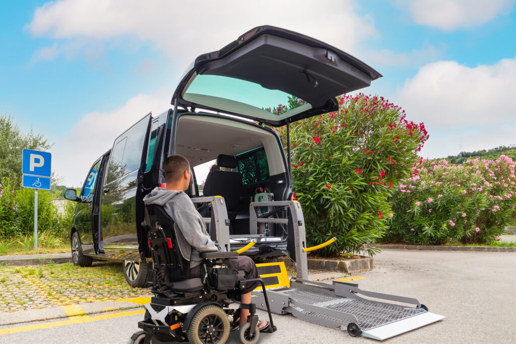 A man in mobility scooter preparing to drive up a ramp into the back of a car