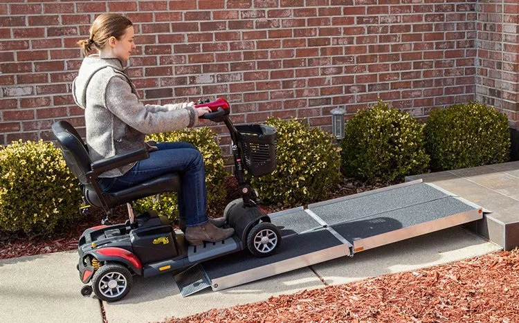 Lady driving a mobility scooter up a ramp that is placed over a step